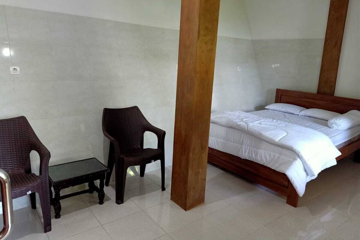 A bedroom with a wooden bed, two wicker chairs, and a small table.