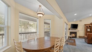 Un salon spacieux avec une grande table à manger en bois, des sièges confortables, une cheminée et un téléviseur.
