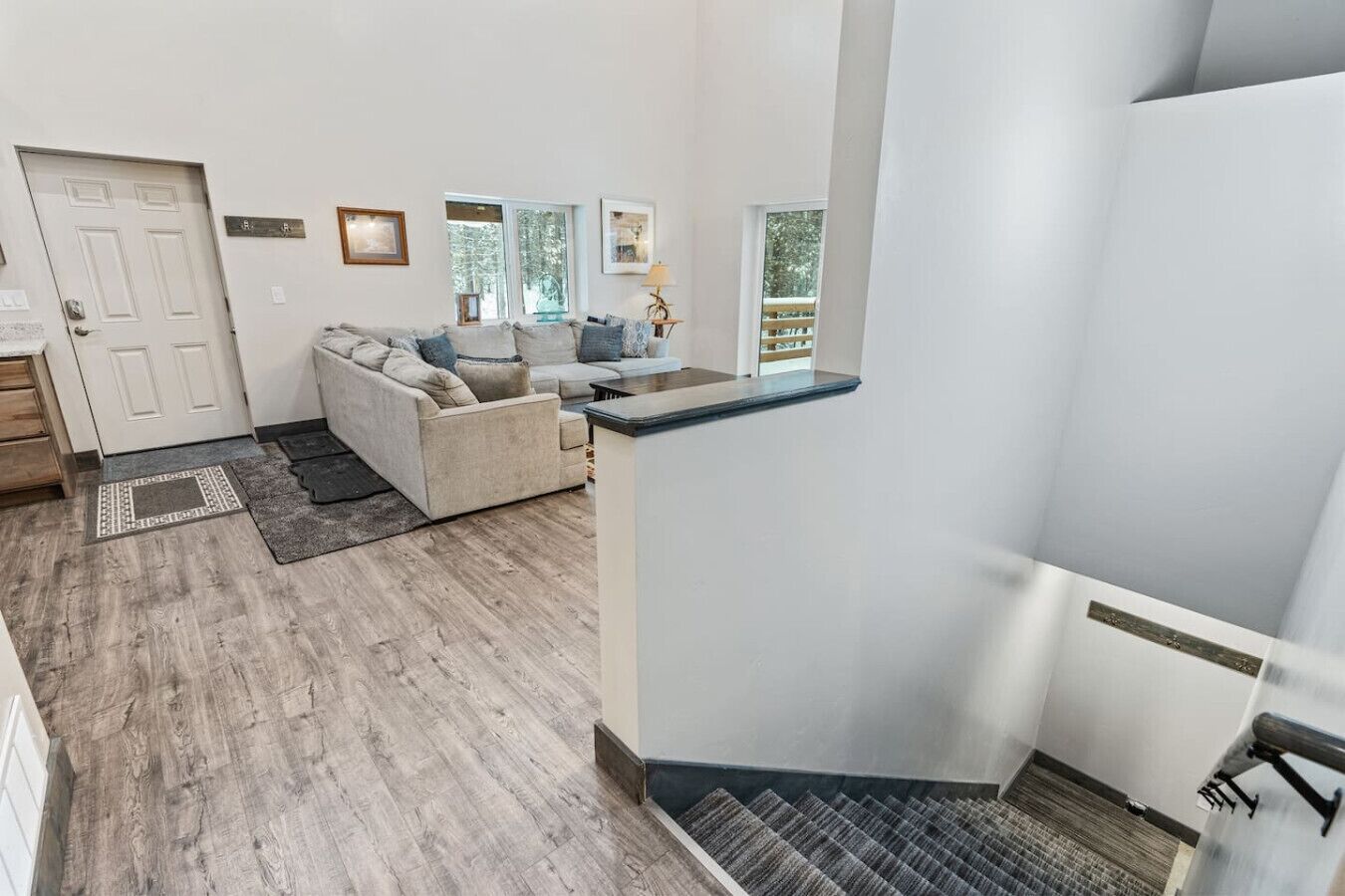 Een ruime woonkamer met een beige bank, een salontafel en uitzicht op het buiten.