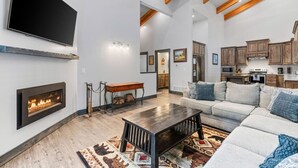A spacious living room with a fireplace, a large TV, and a cozy seating area. - Prism Peaks | Hot Tub, Fire Pit, AC, Yellowstone, ATV, Views! (Island Park)