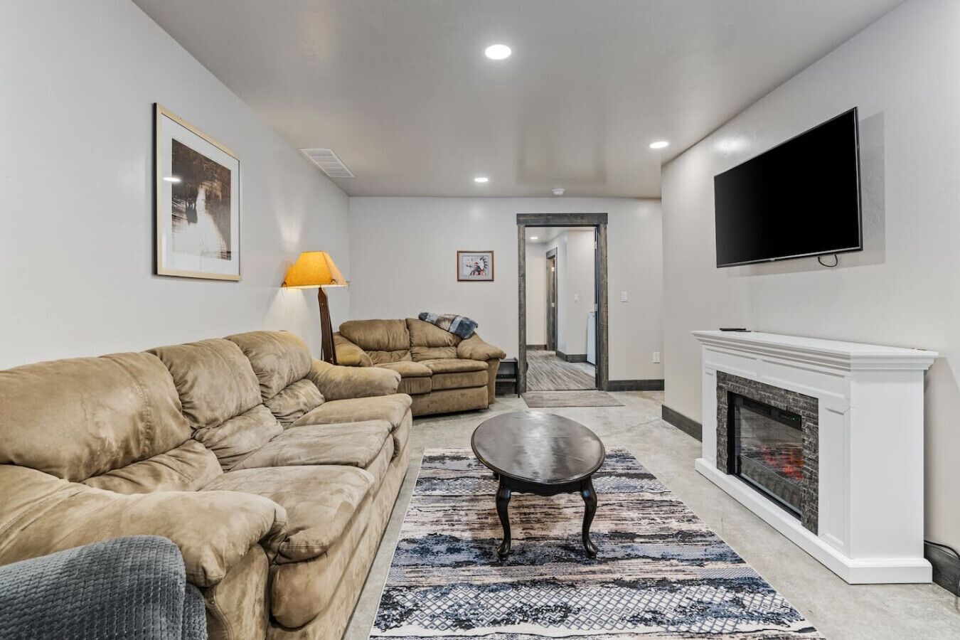 A living room with a beige sofa, a small round table, a fireplace, and a television mounted on the wall.