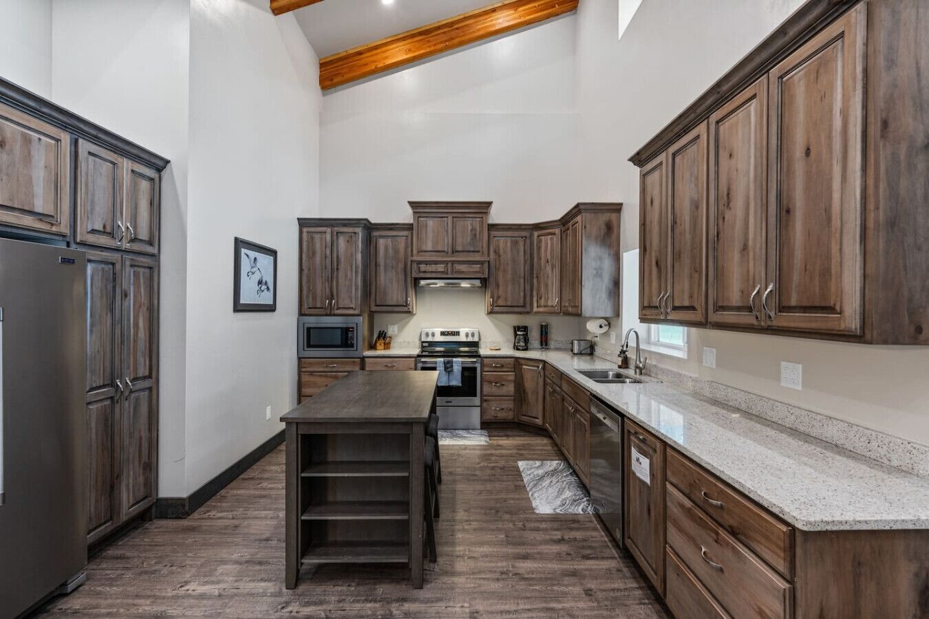 A spacious kitchen with dark wooden cabinets, a granite countertop, and a central island.