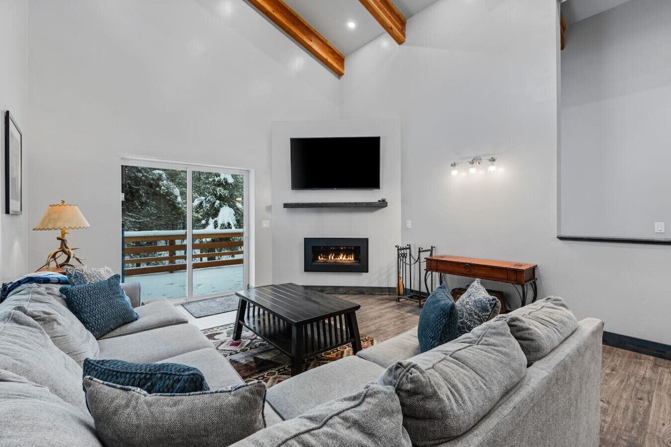 A modern living room with a fireplace, a flat-screen TV, and a large sofa.