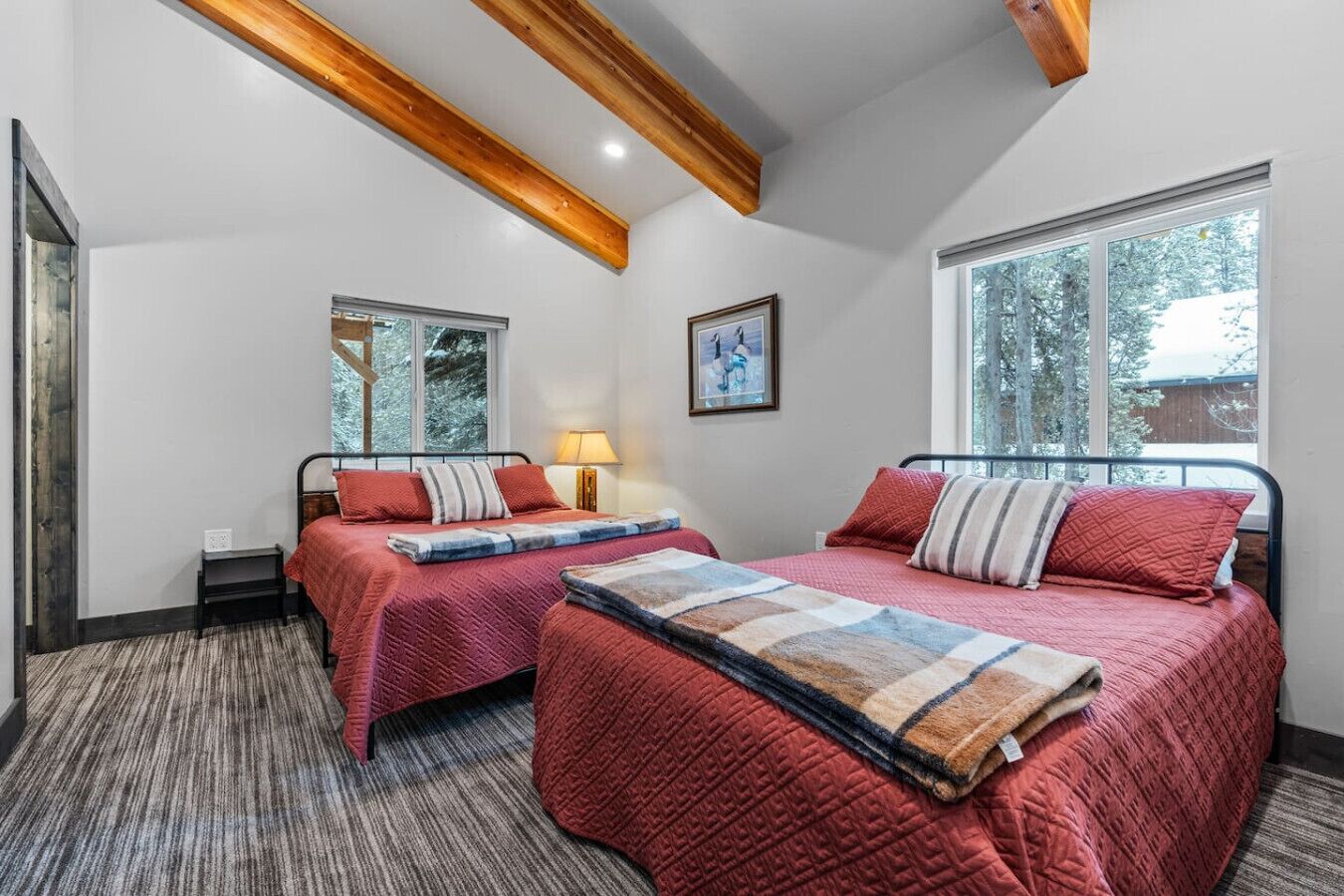 A bedroom with two beds, a window, and a lamp.