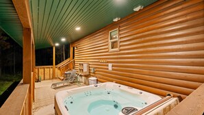 Eine Holzhütte mit Whirlpool, einer überdachten Terrasse und einem Fenster.
