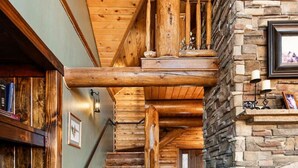 Un escalier en bois, une cheminée en pierre et une bibliothèque.