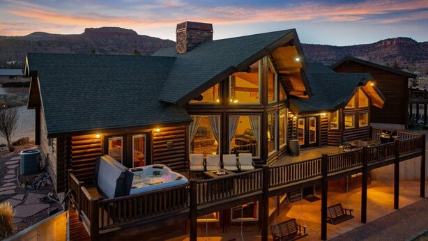 Une cabane en rondins dotée d’une terrasse, d’un espace salon extérieur et d’un jacuzzi.
