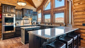 Une cuisine spacieuse dotée de meubles en bois foncé, d’appareils électroménagers en acier inoxydable et d’un grand îlot central avec des tabourets de bar.