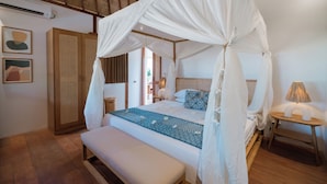 A bedroom with a four-poster canopy bed, a bench, a bedside table with a lamp, and a wardrobe.