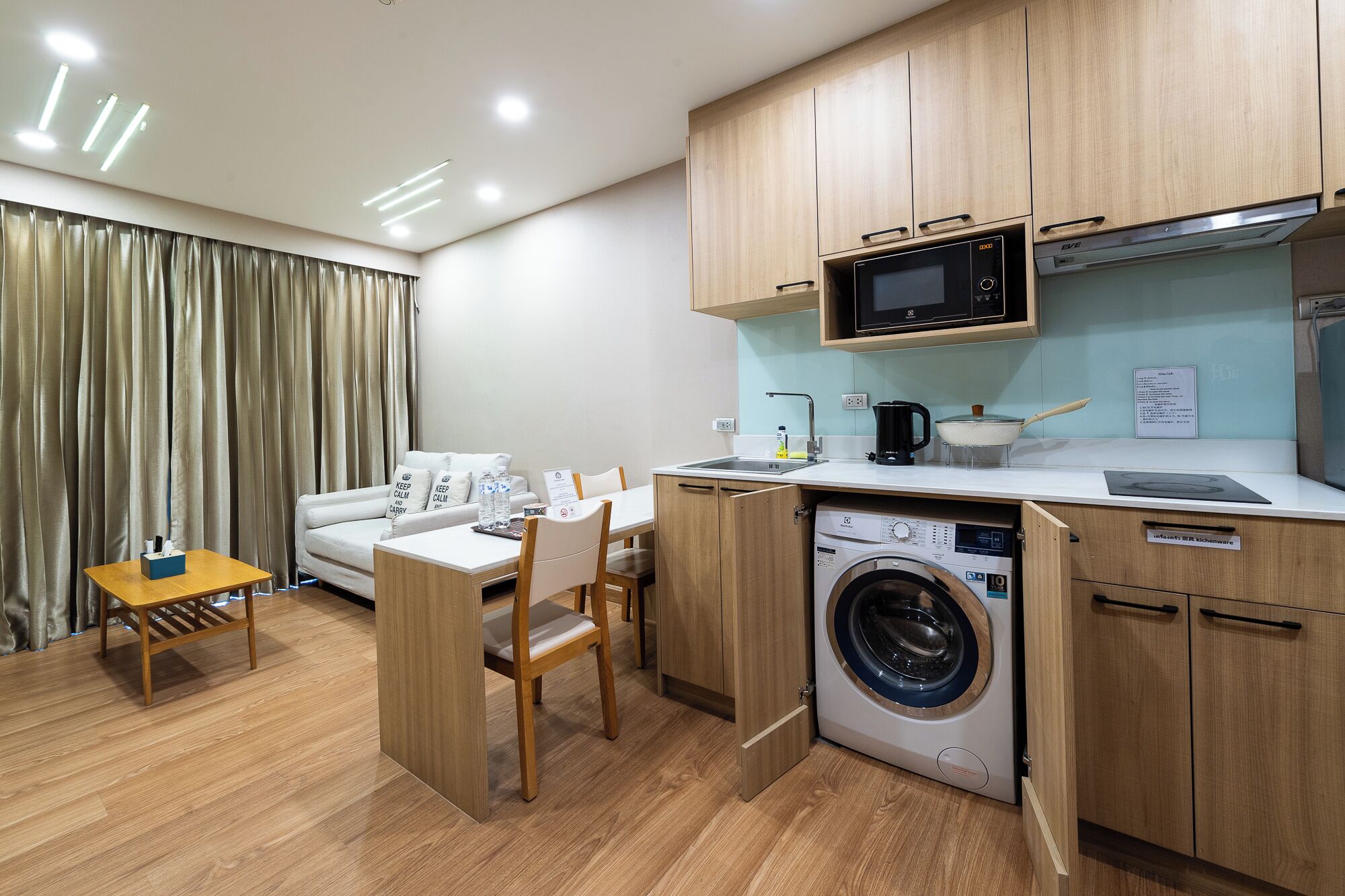 A compact kitchenette with a microwave, stove, and washing machine.