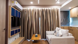 A modern living room with a sofa, a small wooden table, and a TV mounted on a wall. - Pleasant Chiangmai (Chiang Mai)