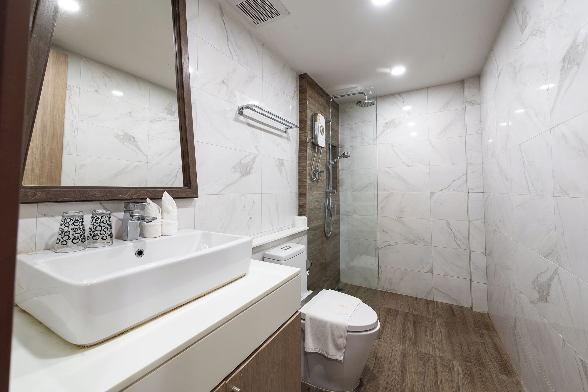 A modern bathroom with a large white sink, a mirror, a shower, and a toilet.