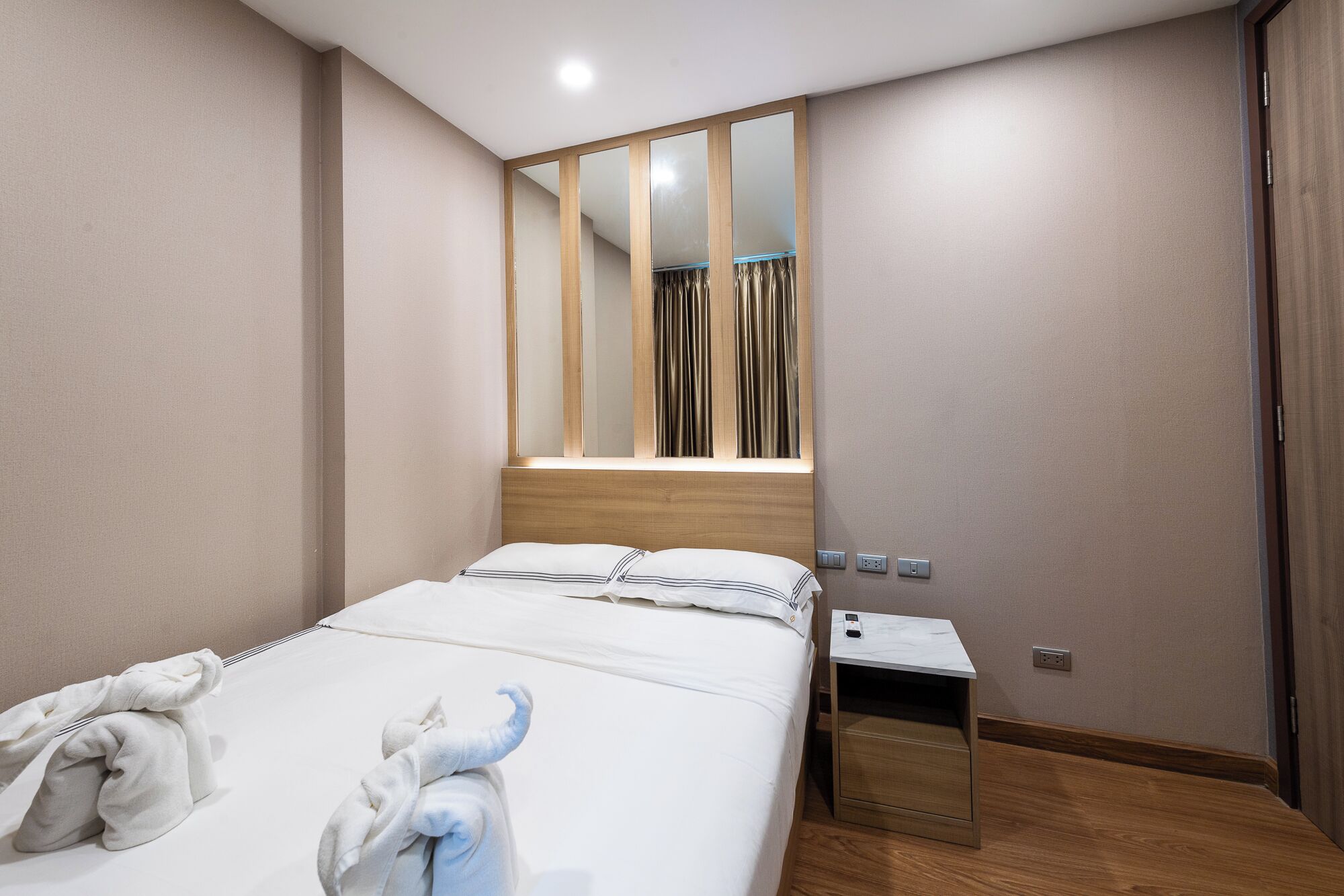 Una habitación de hotel con una cama, una mesita de noche, un espejo y un buró de madera.
