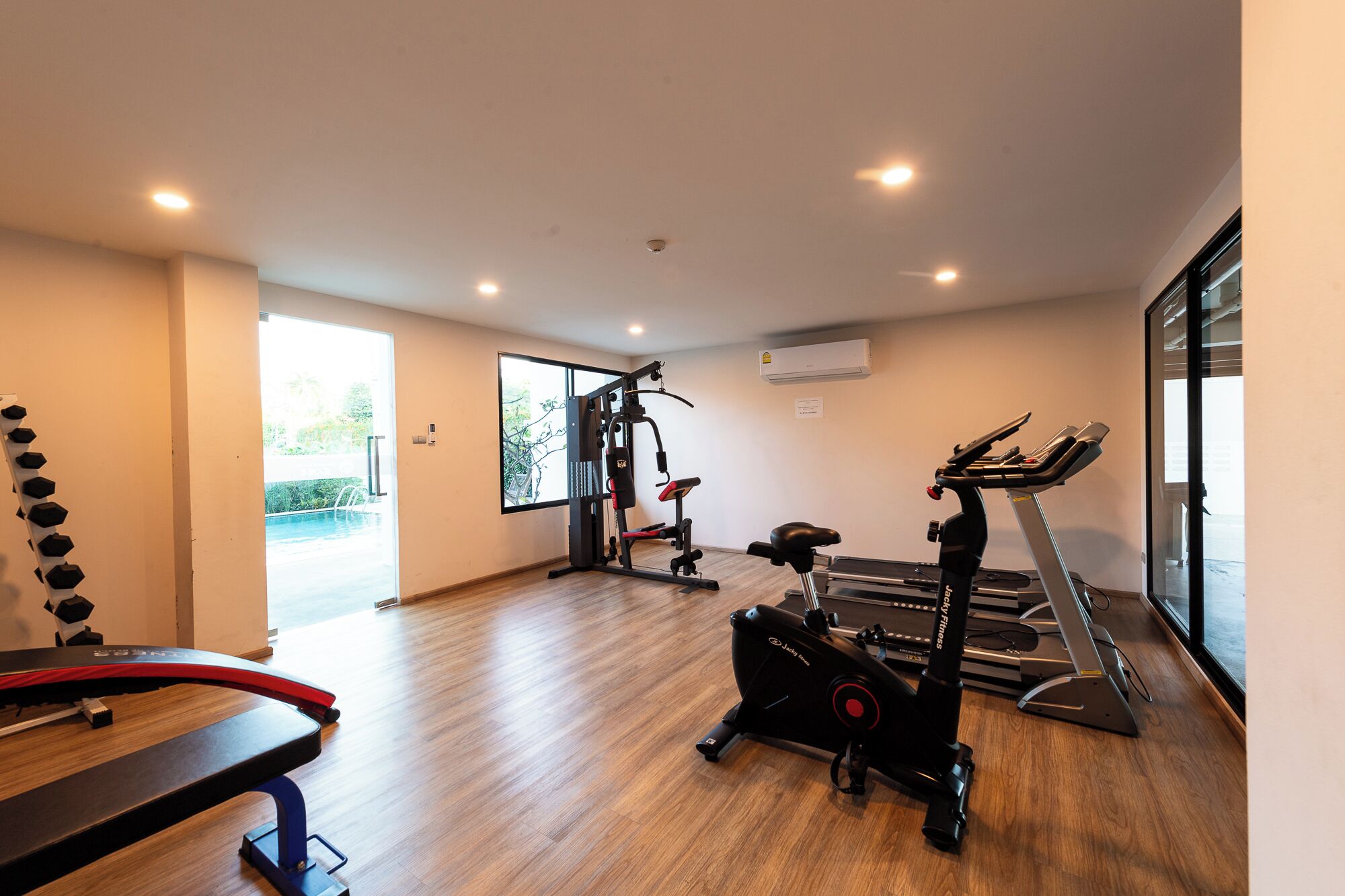 A modern gym with a treadmill, elliptical, and weight machine.