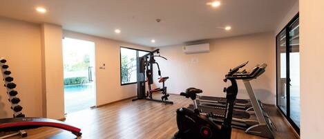 A modern gym with a treadmill, elliptical, and weight machine.
