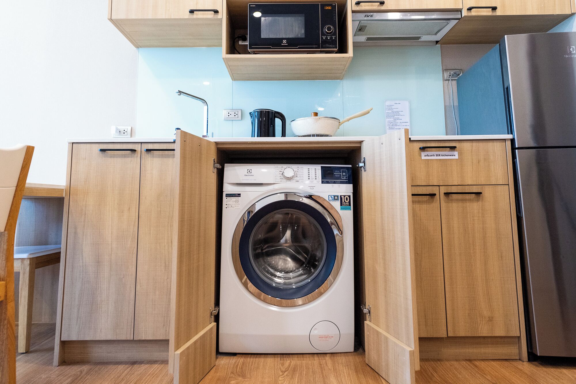 Una cocina compacta con armarios de madera, lavadora, microondas y refrigerador.