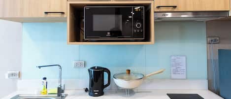 Une cuisine équipée d’un four à micro-ondes, d’une bouilloire, d’une cuisinière et d’un évier.