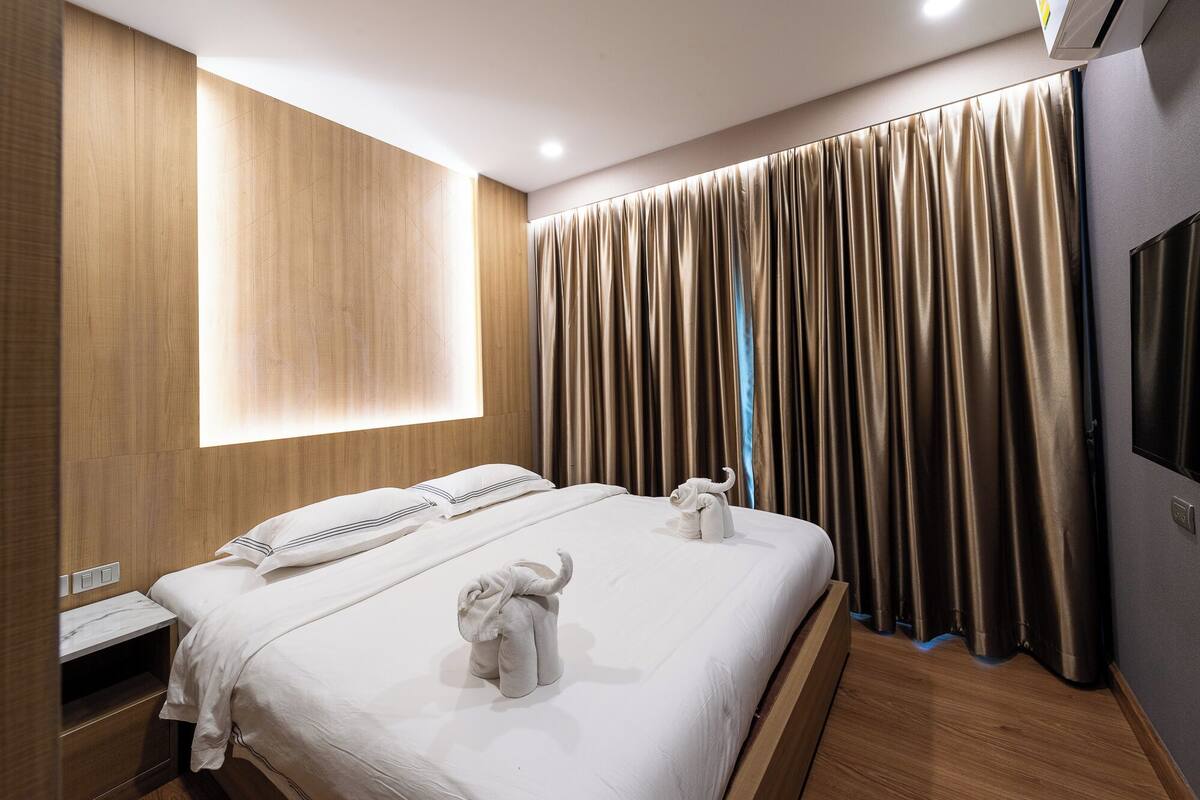 A modern hotel room with a large bed, two plush pillows, a nightstand, and a TV.