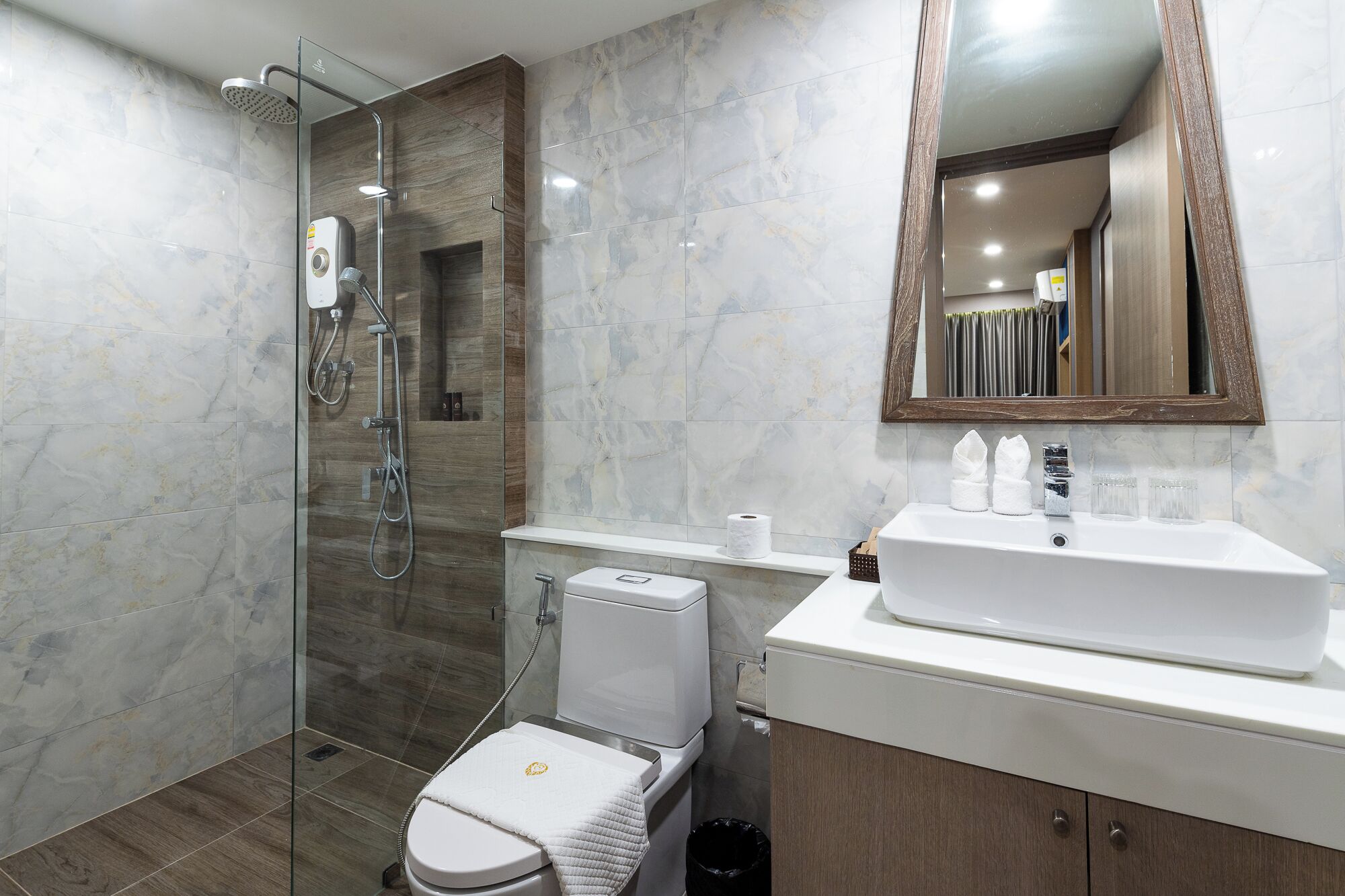 Un baño moderno con ducha envuelta en vidrio, inodoro blanco y tocador con espejo.