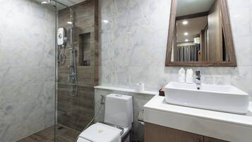 A modern bathroom with a glass-enclosed shower, a white toilet, and a vanity with a mirror.