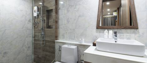 Un baño moderno con ducha envuelta en vidrio, inodoro blanco y tocador con espejo.