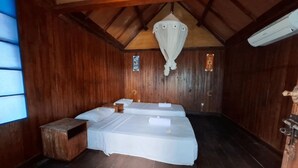 A wooden room with two beds, a small wooden table, and a hanging light fixture. - Brown Sugar Homestay (Gili Trawangan)