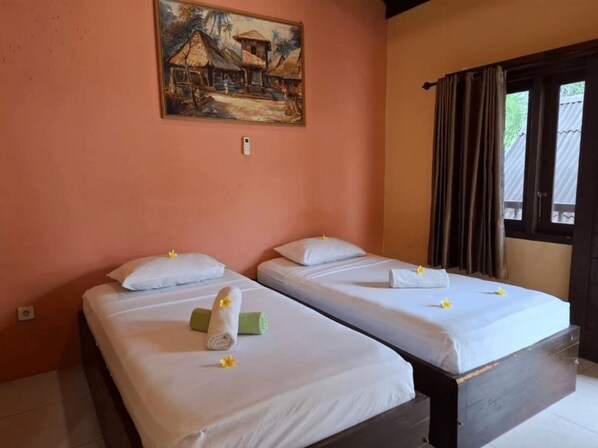 A room with two beds, each with white linens and a rolled towel. There is a painting on the wall above the beds, and a window with curtains to the right. - Brown Sugar Homestay (Gili Trawangan)