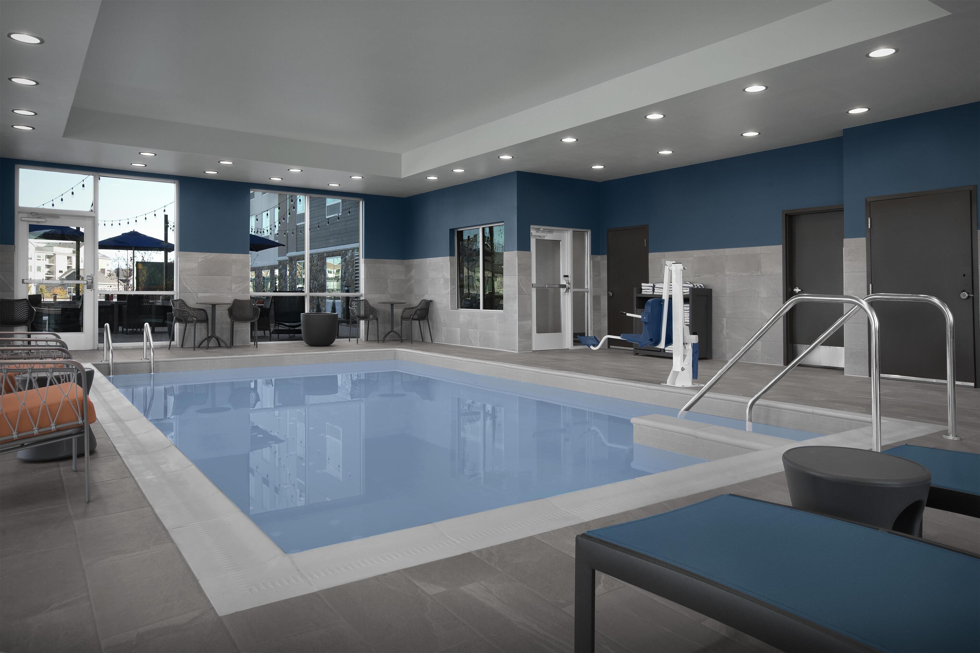 A swimming pool area with a seating area, tables, and chairs.
