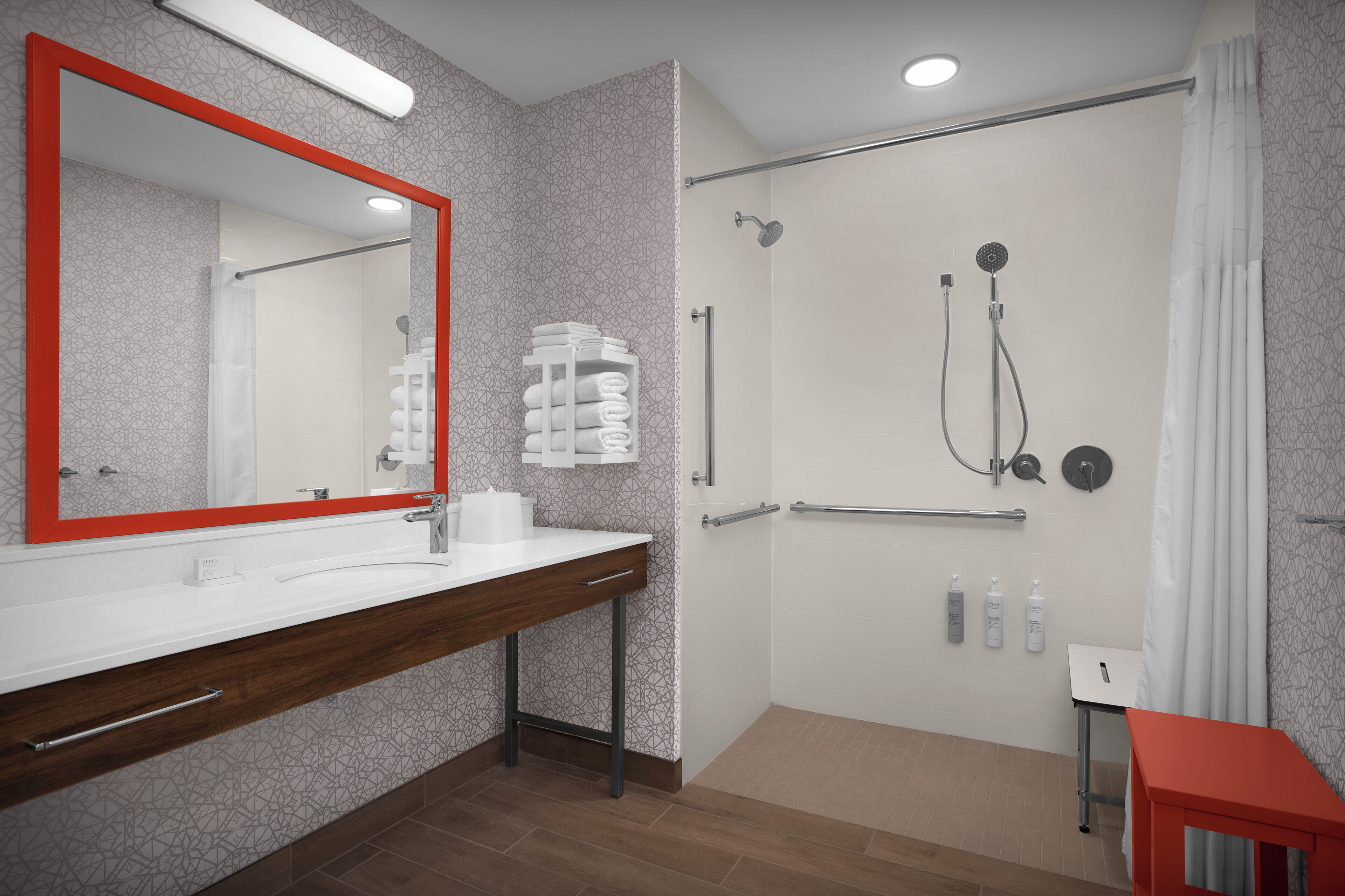 A modern bathroom with a large mirror, a shower with a handheld showerhead, and a vanity with a towel rack.