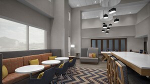 Een moderne hotel lobby met een zithoek, een lange tafel en een kamerbreed tapijt.