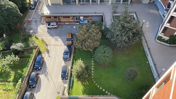 Eine Vogelperspektive auf ein mehrstöckiges Gebäude mit Parkplatz, Grünflächen und blauem Himmel.