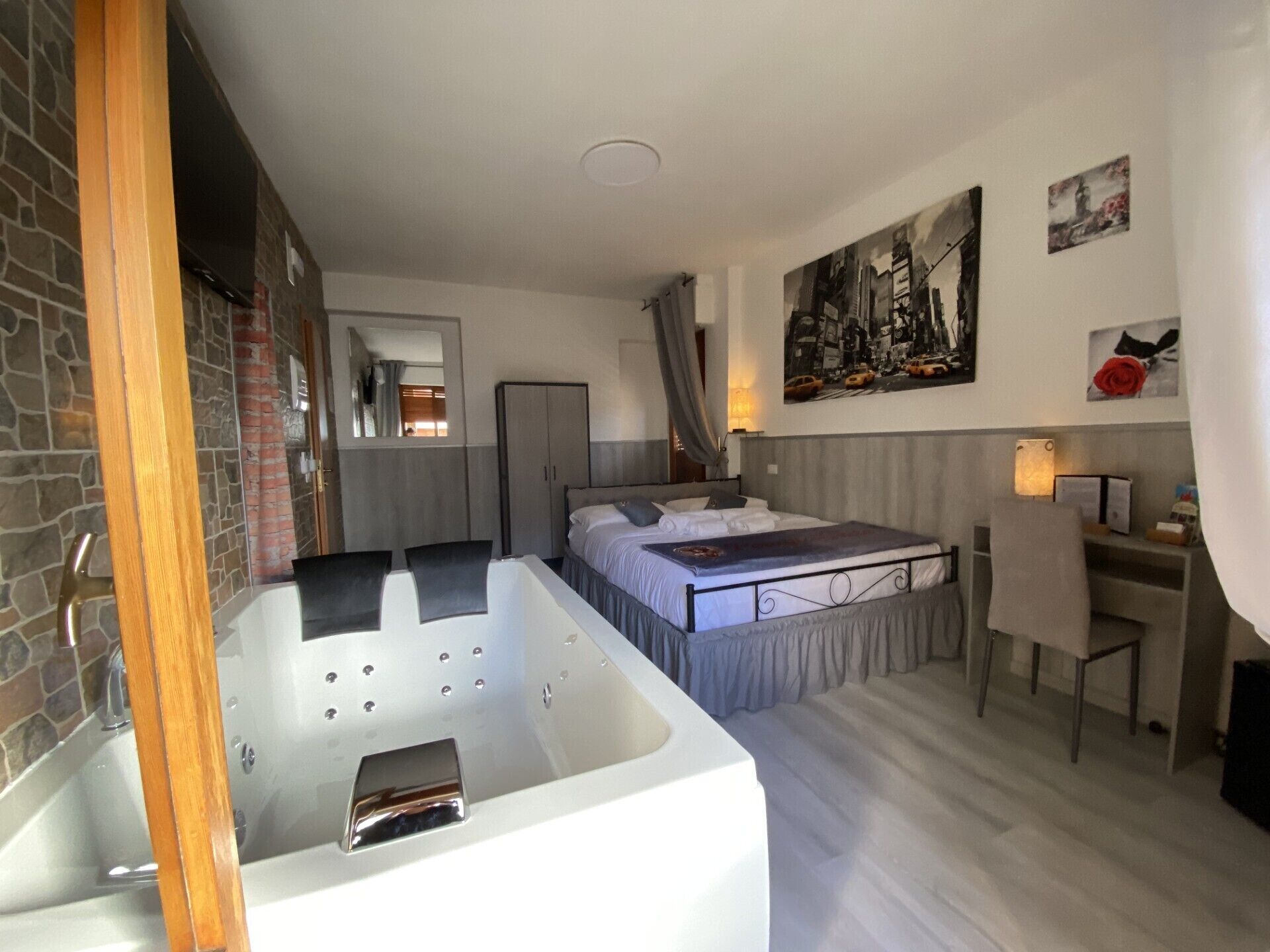 Un dormitorio moderno con una cama grande, un escritorio independiente, una bañera y un armario.