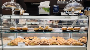 Une vitrine de pâtisserie présentant divers gâteaux et une machine à café.