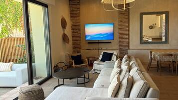 A modern living room with a sectional sofa, a flat-screen TV, and a dining area.