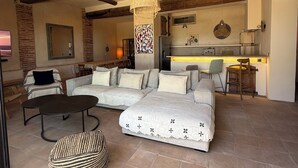 Una sala de estar con un sofá, dos sillones, una mesita de centro y una lámpara colgante.