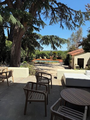 Un patio con mobiliario de madera, una piscina y vistas del paisaje.