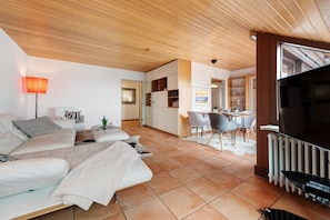 Una sala de estar moderna con un sofá, un televisor y un comedor con sillas.