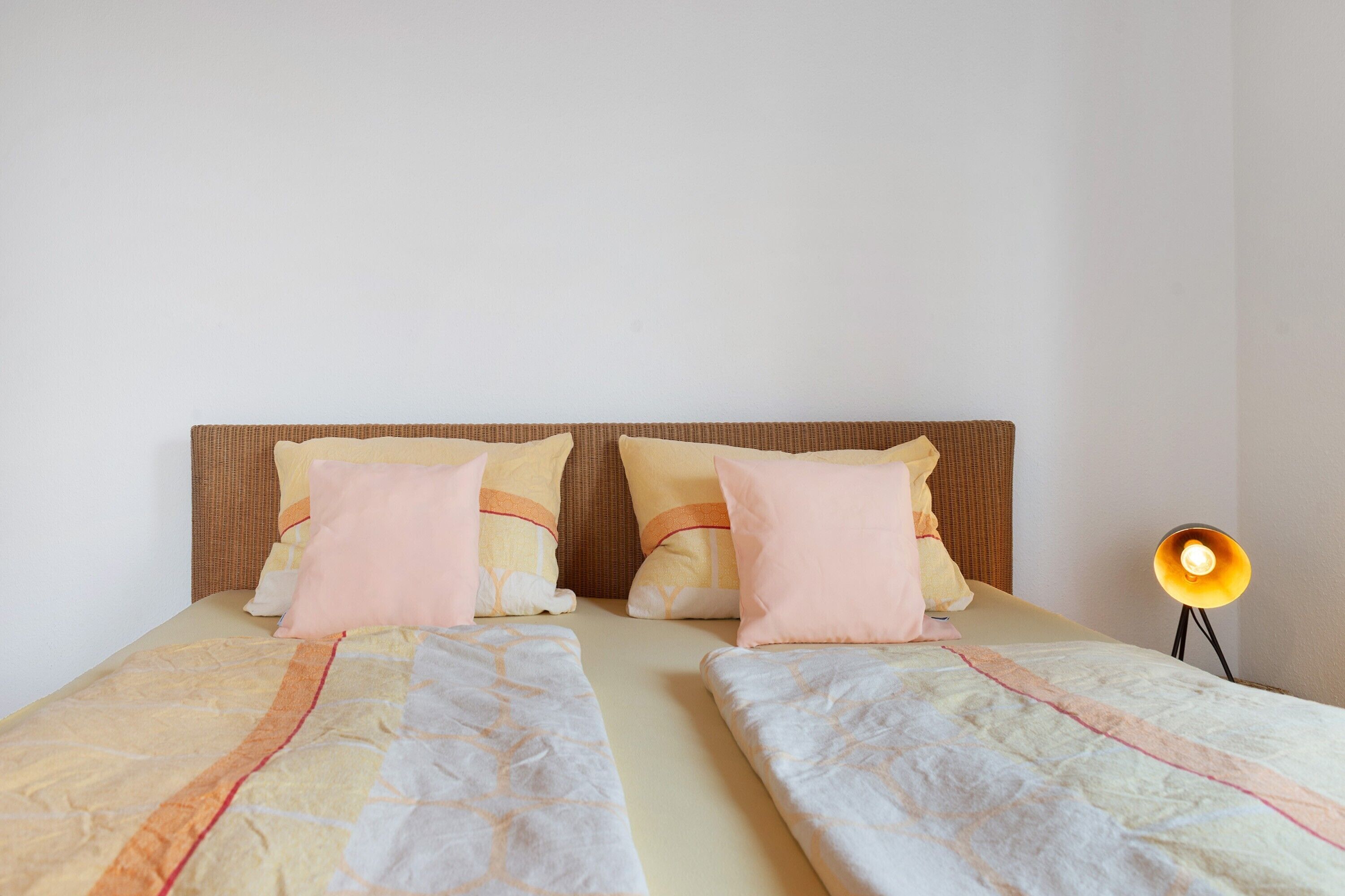Cama doble con dos almohadas, lámpara de noche y cabecero.