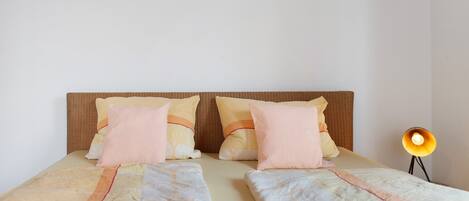 Cama doble con dos almohadas, lámpara de noche y cabecero.