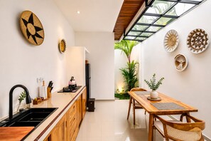 Une cuisine moderne avec un évier noir, des meubles en bois et une bouilloire noire posée sur le plan de travail.