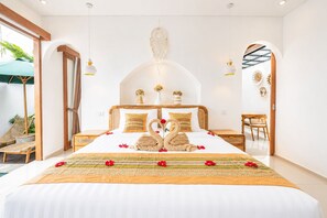 A spacious bedroom with a large bed, wooden headboard, and a decorative swan centerpiece.