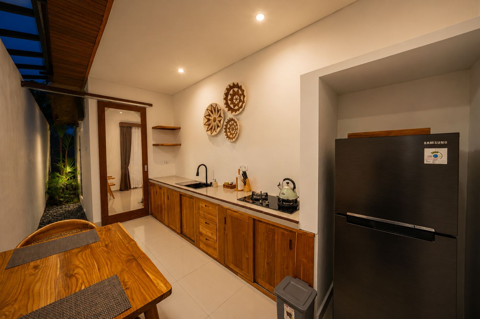 Una cocina moderna con armarios de madera, un refrigerador de acero inoxidable y un comedor con mesa y sillas.