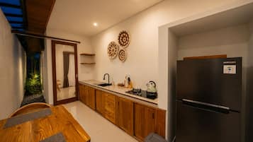 Una cocina moderna con armarios de madera, un refrigerador de acero inoxidable y un comedor con mesa y sillas.