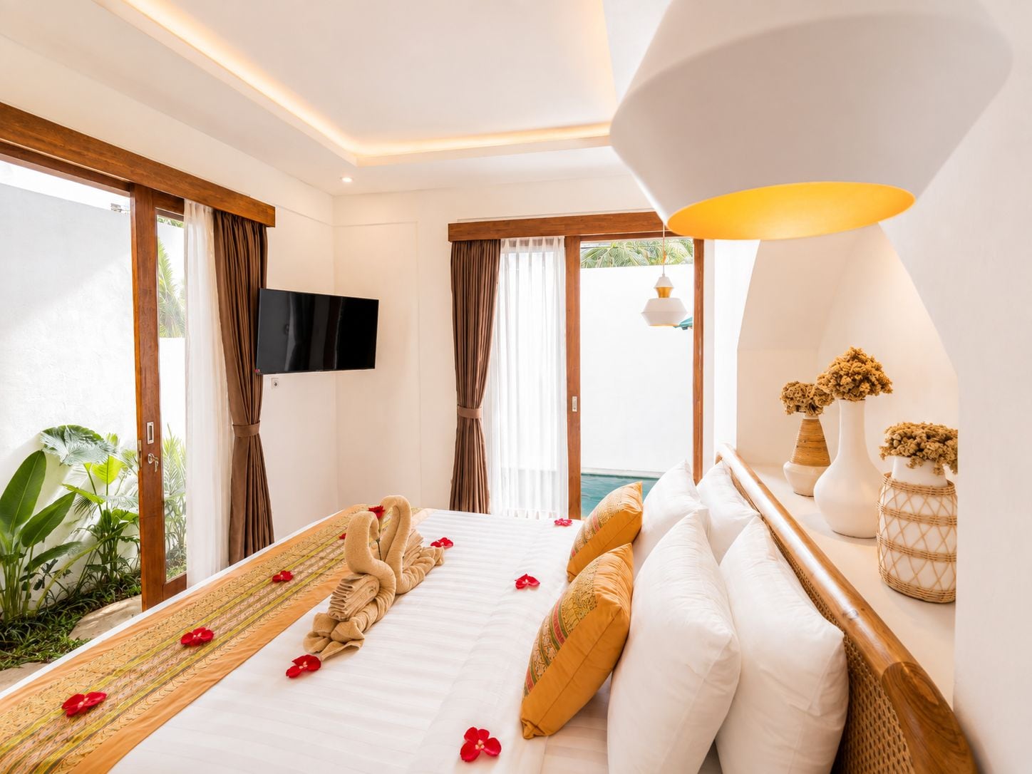 Habitación de hotel con cama, televisor y vista al exterior.