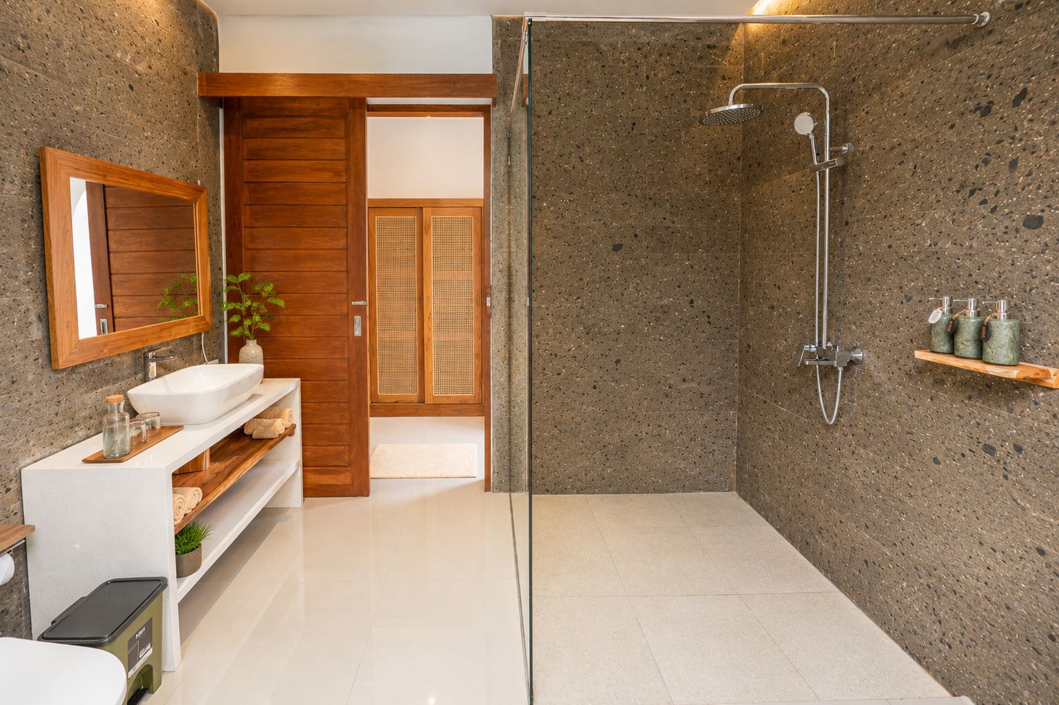 Un baño moderno con cabina de ducha de vidrio, lavabo blanco y tocador de madera.