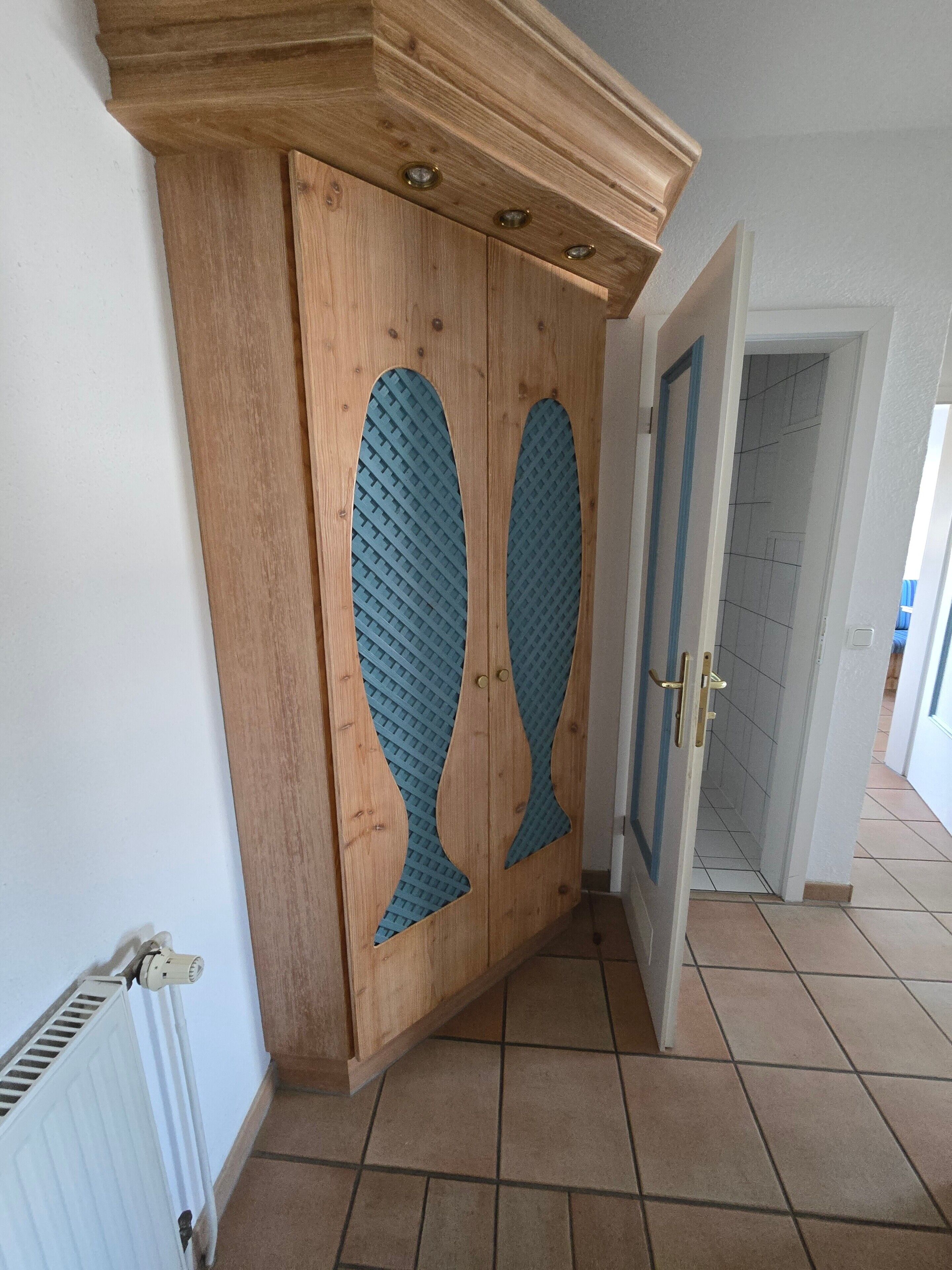 A hallway with a wooden wardrobe featuring two large doors with a blue geometric pattern.