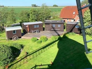A row of mobile homes with a wooden deck and a small table and chairs. - Mobile Home 'Traumwagen An Der Mühle' with Private Terrace, Shared Garden and Wi-Fi (Nordermeldorf)