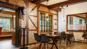 Interior de un restaurante con paredes de ladrillo, vigas de madera, piso de baldosas y un comedor con mesas y sillas.