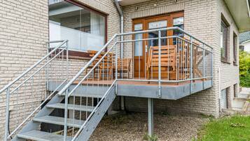 Ein Gebäude mit Backsteinfassade, einer hölzernen Terrasse mit Bänken und einer Metalltreppe, die zu einem Balkon im zweiten Stock führt.