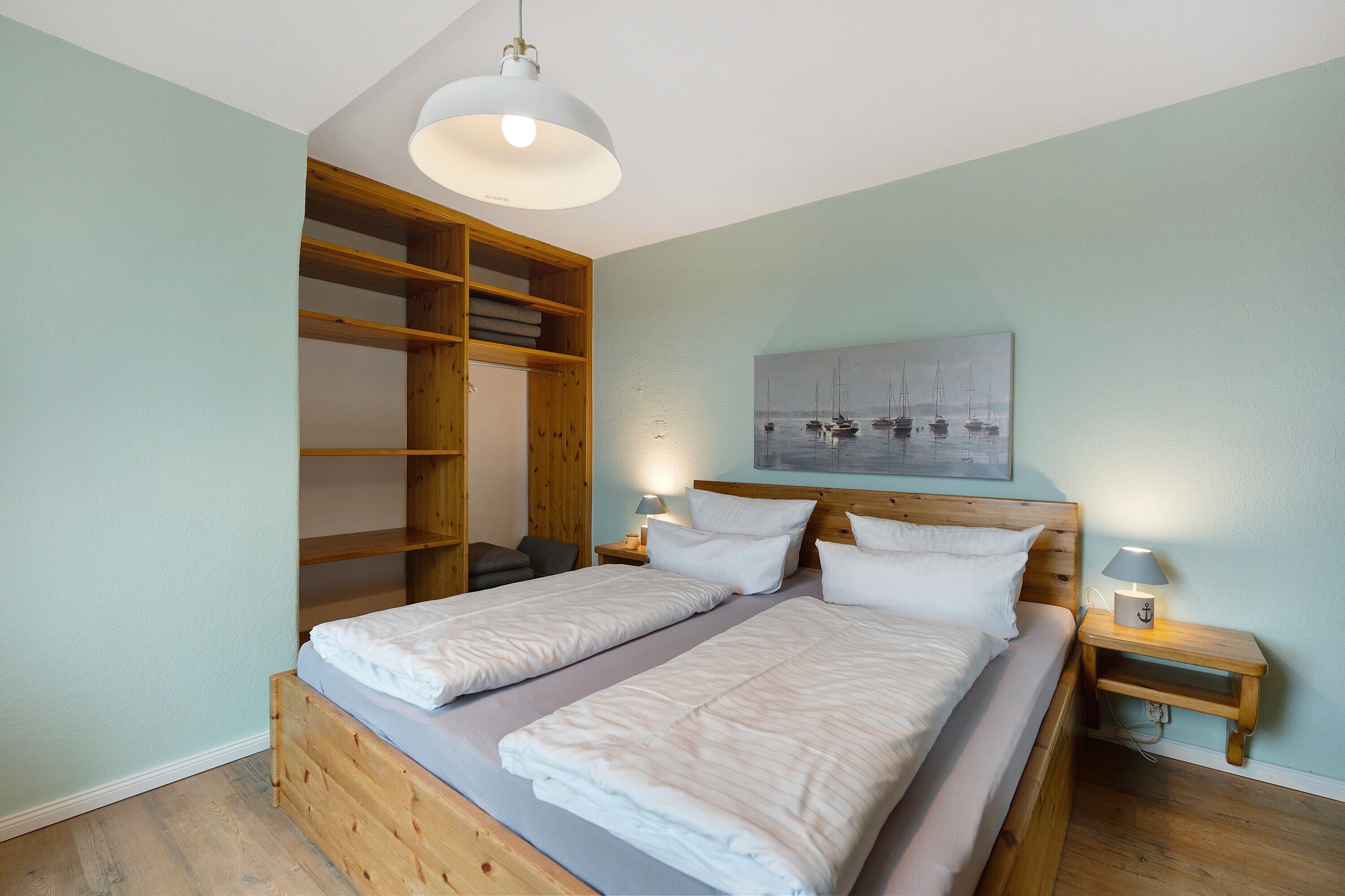 Une chambre avec deux lits, une tête de lit en bois, une grande armoire et un tableau au mur.
